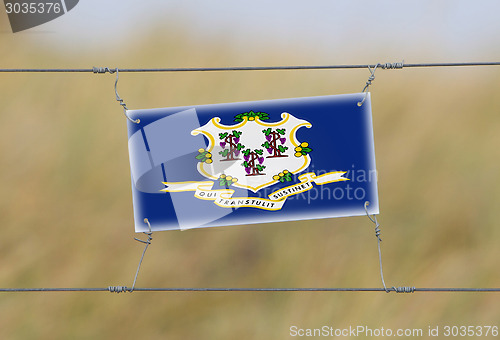 Image of Border fence - Old plastic sign with a flag