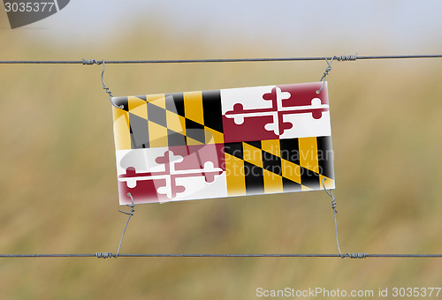 Image of Border fence - Old plastic sign with a flag