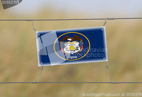 Image of Border fence - Old plastic sign with a flag