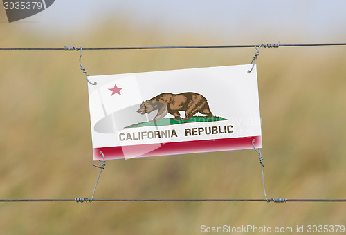 Image of Border fence - Old plastic sign with a flag