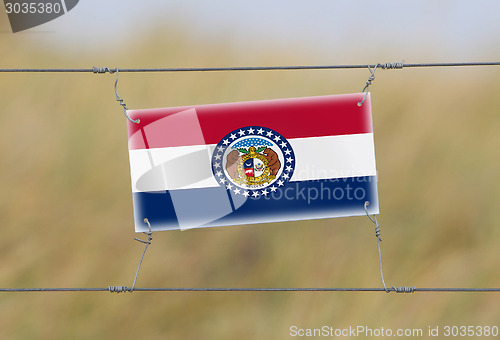 Image of Border fence - Old plastic sign with a flag