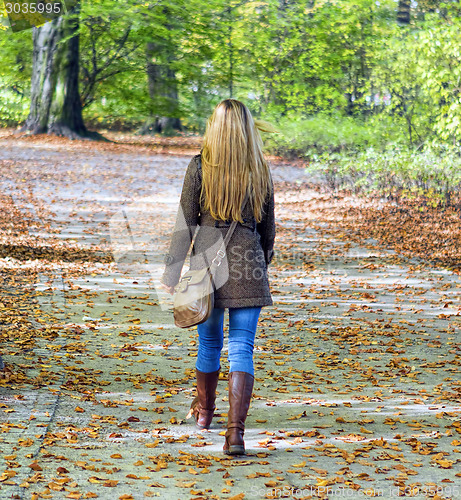 Image of Young woman walking in park