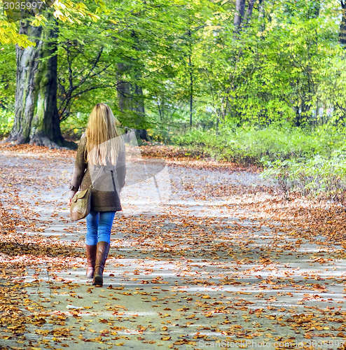 Image of Young woman walking in park