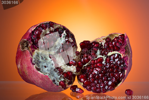 Image of Ripe red pomegranate, break in half, juicy corn