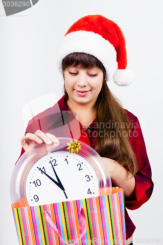 Image of blue-eyed beautiful girl in santa hat with clock