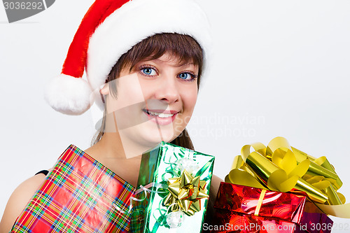 Image of blue-eyed beautiful girl in santa hat with presents