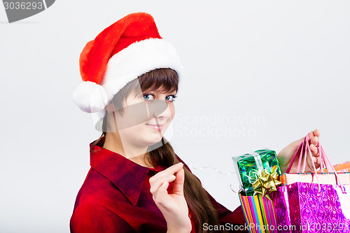 Image of blue-eyed beautiful girl in santa hat with presents