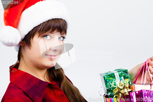 Image of blue-eyed beautiful girl in santa hat with presents