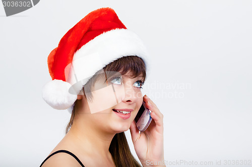 Image of blue-eyed beautiful girl in santa hat with phone