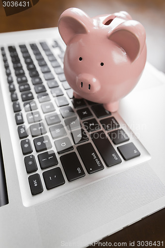 Image of Piggy Bank Resting on Laptop Computer