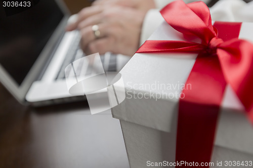 Image of White Gift Box with Red Bow Near Man using Laptop