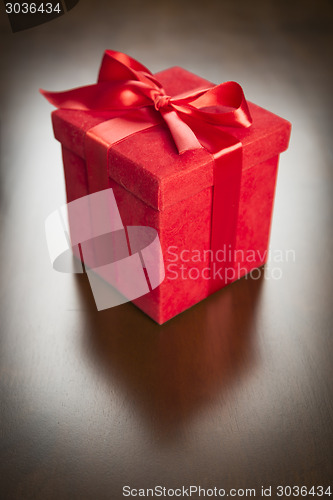 Image of Red Gift Box with Ribbon and Bow Resting on Wood