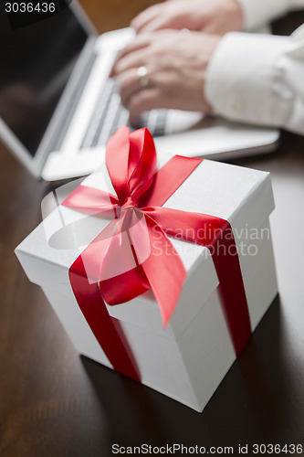 Image of White Gift Box with Red Bow Near Man using Laptop