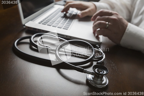 Image of Stethoscope near Man Typing on Laptop Computer