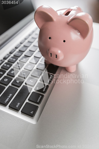 Image of Piggy Bank Resting on Laptop Computer