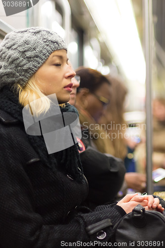 Image of Woman napping on subway full of people.