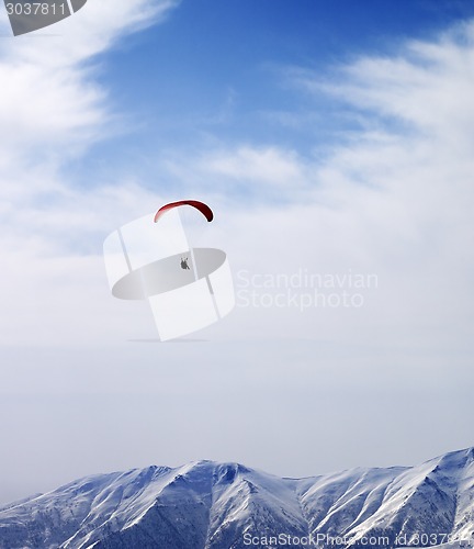 Image of Paraglider silhouette of mountains in windy sky at sun day