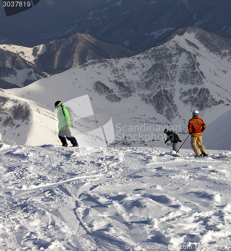 Image of Snowboarders and skier on off-piste slope in sun evening