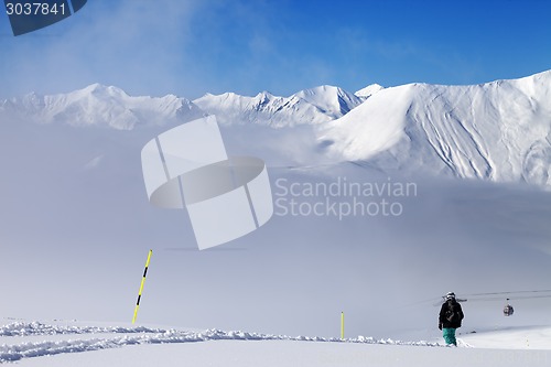 Image of Snowboarder on off-piste slope and mountains in mist