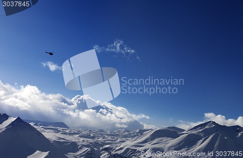 Image of Helicopter above snowy plateau and sunny sky