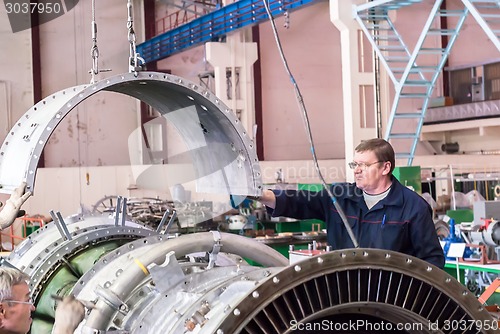 Image of Elderly mechanic assembles aviation engine