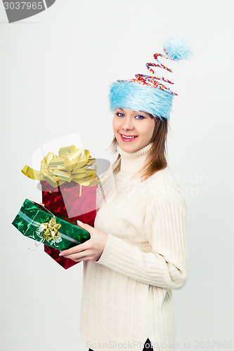 Image of happy girl in an unusual Christmas hat with gift boxes