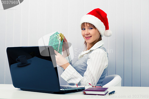 Image of girl in the office in Santa hats with a laptop and a gift