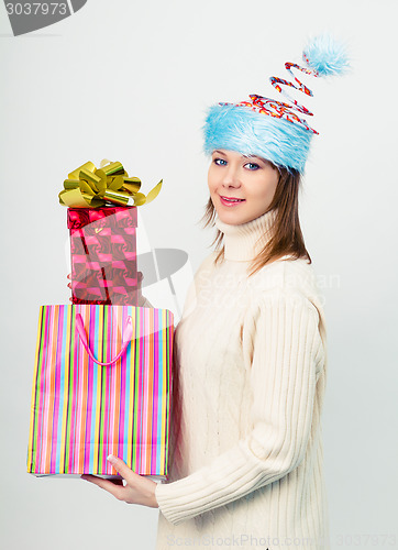 Image of happy girl in an unusual Christmas hat with gift boxes