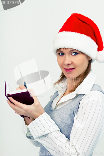 Image of happy girl in santa hat with a notebook