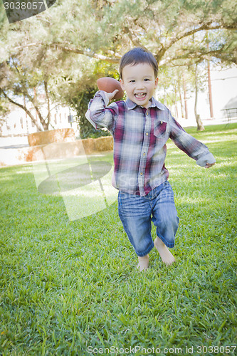Image of Cute Young Mixed Race Boy Playing Football Outside