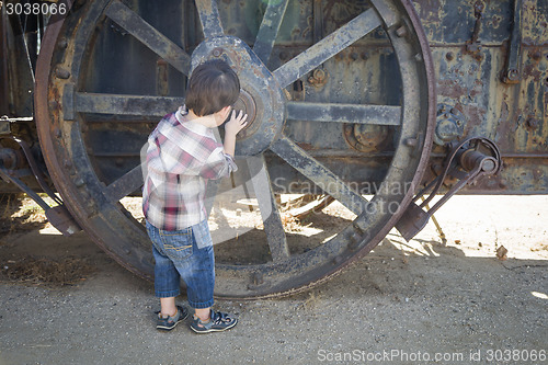 Image of Cute Young Mixed Race Boy Having Fun Near Antique Machinery