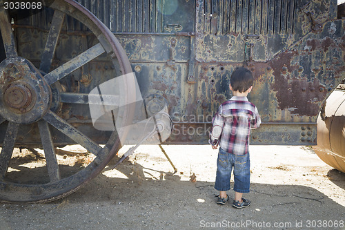 Image of Cute Young Mixed Race Boy Having Fun Near Antique Machinery