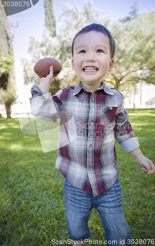 Image of Cute Young Mixed Race Boy Playing Football Outside
