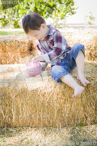 Image of Cute Young Mixed Race Boy Putting Coins Into Piggy Bank