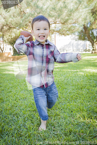 Image of Cute Young Mixed Race Boy Playing Football Outside