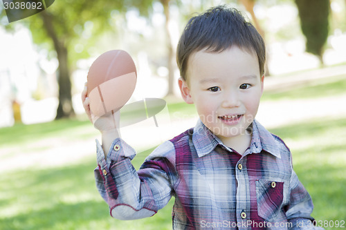 Image of Cute Young Mixed Race Boy Playing Football Outside