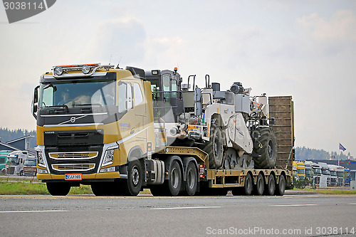 Image of Yellow Volvo FH Hauls Heavy Machinery