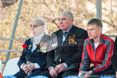 Image of Senior veterans of World War II and boy on tribune