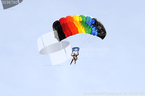 Image of the parachutist goes down on a multi-colored parachute.