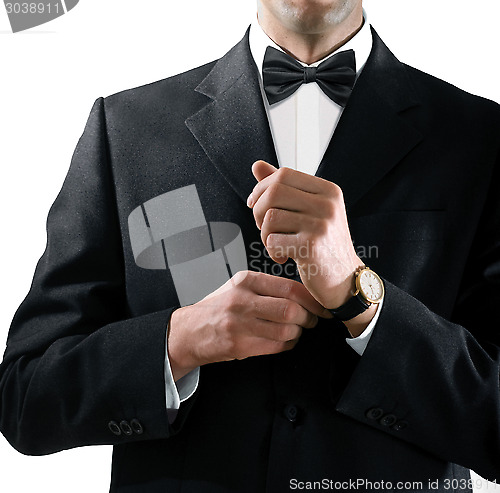 Image of man in tuxedo puts on watch