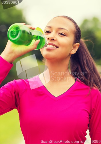 Image of smiling woman drinking from bottle