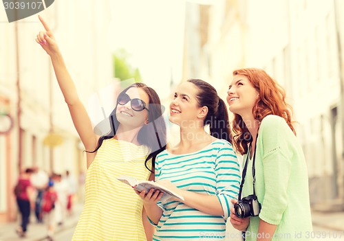 Image of smiling teenage girls with city guide and camera