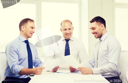 Image of smiling businessmen with papers in office