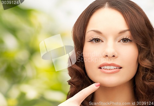 Image of beautiful young woman pointing finger to her chin
