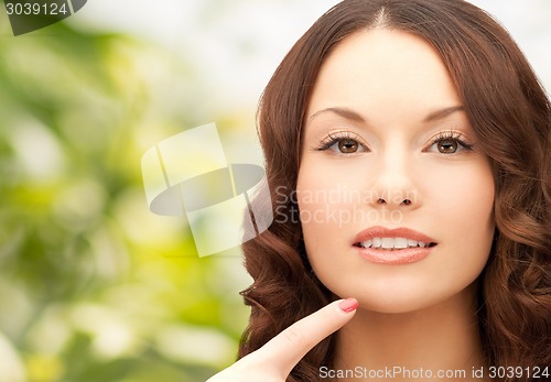 Image of beautiful young woman pointing finger to her chin