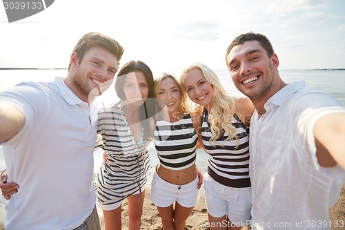 Image of happy friends on beach and taking selfie