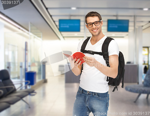 Image of smiling student with backpack and book at airport