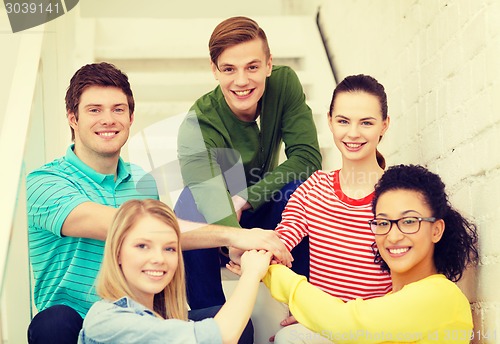 Image of smiling students with hands on top of each other