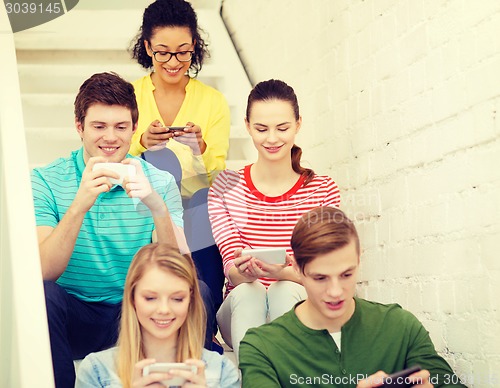 Image of smiling students with smartphone texting at school