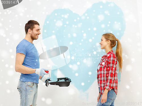 Image of smiling couple painting big heart on wall